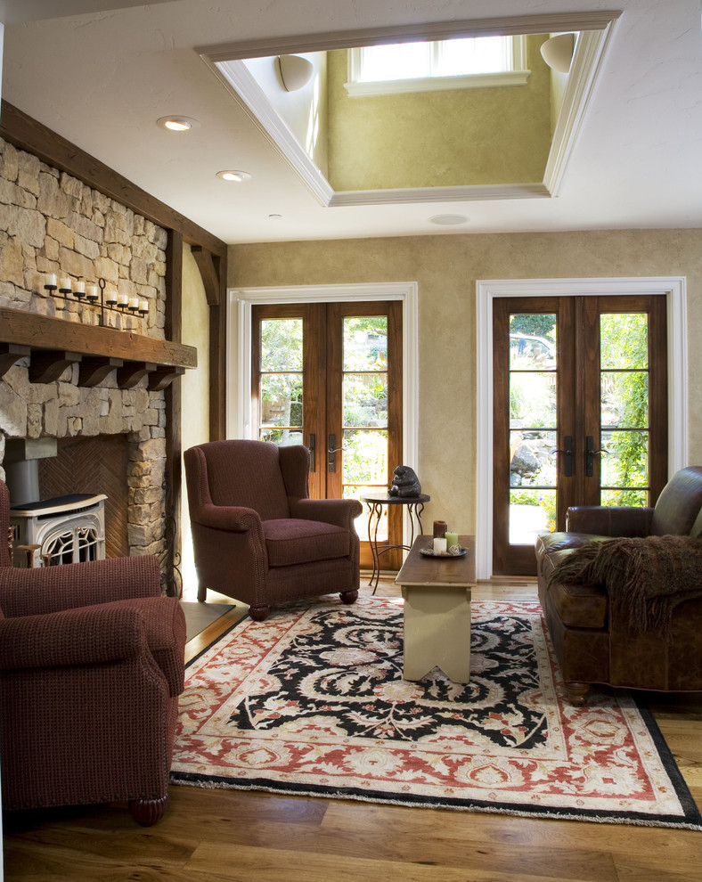 Идея дизайна: гостиная комната в классическом стиле с фасадом камина из камня, печью-буржуйкой и ковром на полу