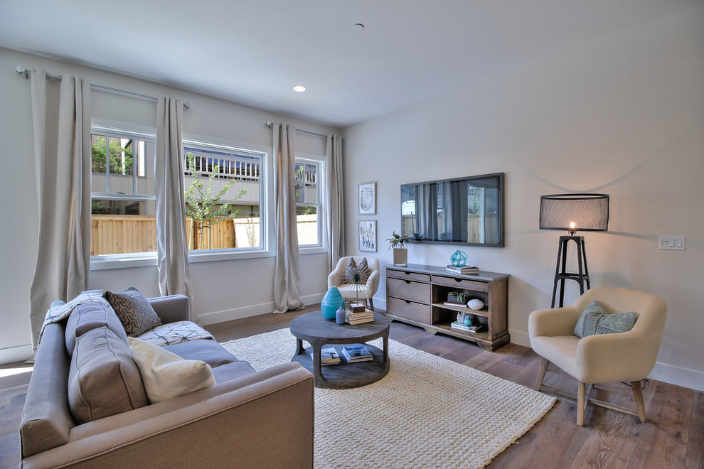 Esempio di un soggiorno aperto con pareti beige, TV a parete e pavimento in legno massello medio