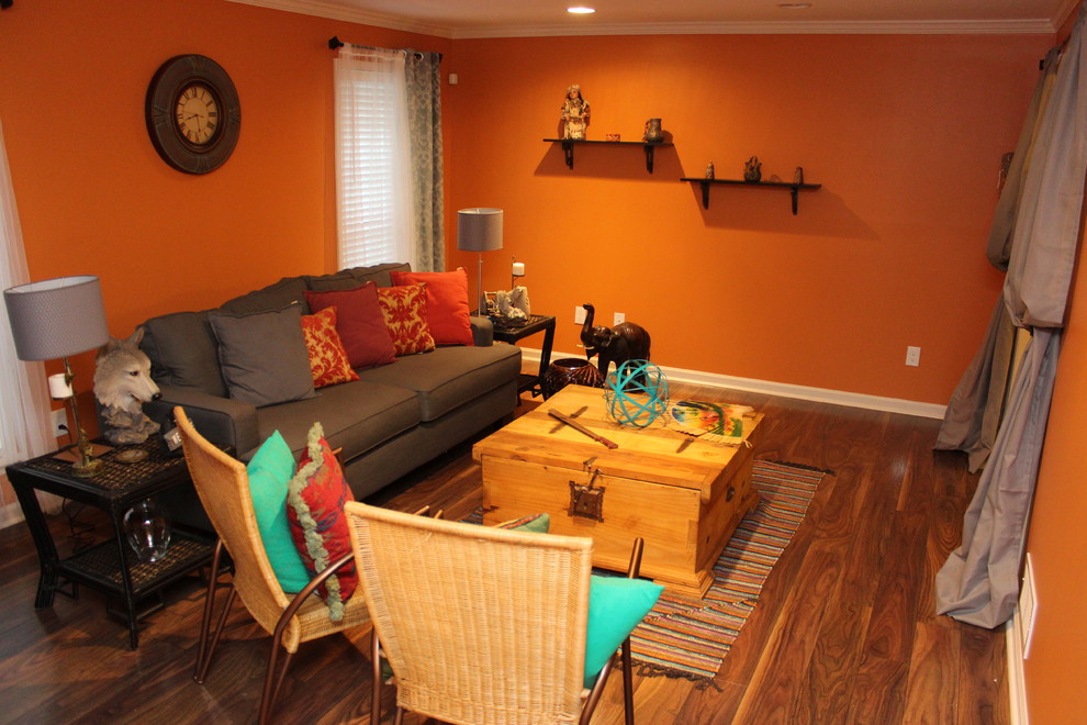 Bild på ett mellanstort amerikanskt separat vardagsrum, med orange väggar och mellanmörkt trägolv