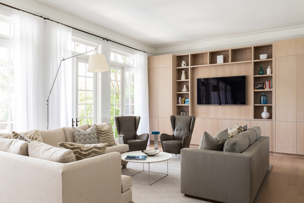 This is an example of a coastal living room in Miami with white walls, medium hardwood flooring and a built-in media unit.