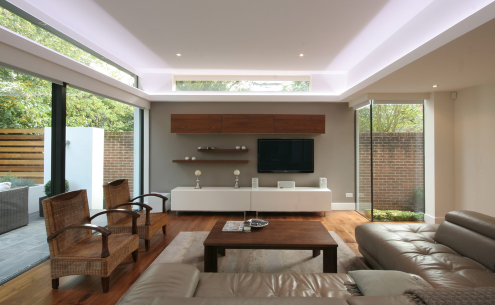 Inspiration för ett mellanstort funkis separat vardagsrum, med ett finrum, beige väggar, mellanmörkt trägolv och en väggmonterad TV