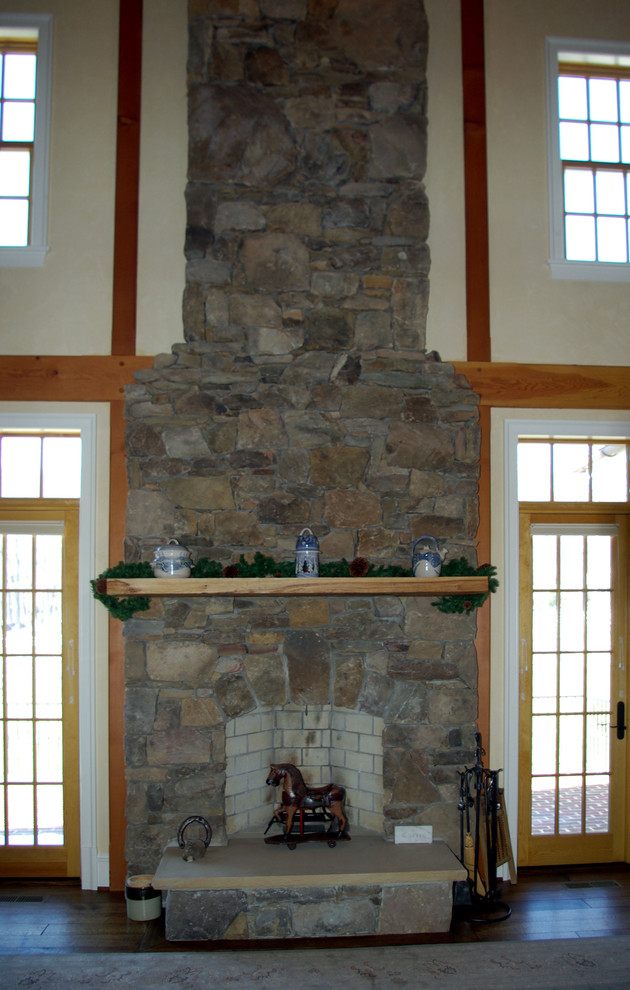 Idée de décoration pour un salon tradition avec un mur beige, parquet foncé, une cheminée standard et un manteau de cheminée en pierre.
