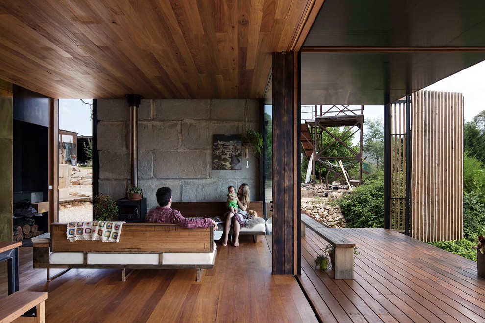 Idées déco pour un salon moderne avec un sol en bois brun, un poêle à bois et un mur en pierre.