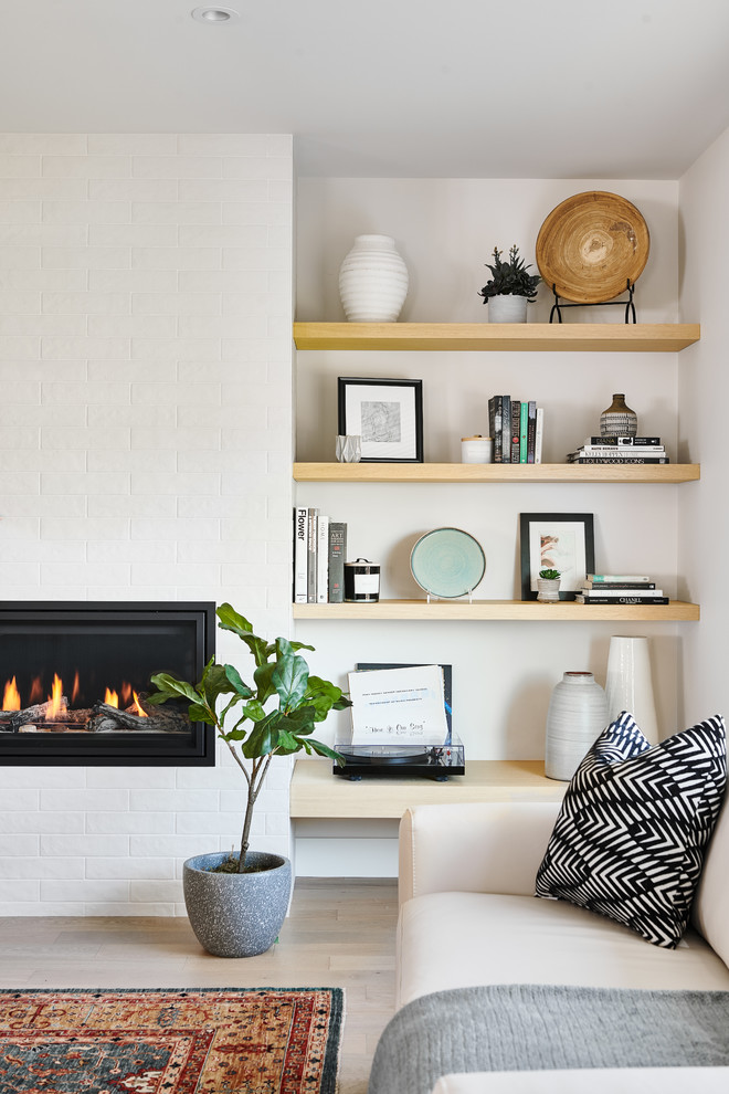 バンクーバーにあるお手頃価格の中くらいな北欧スタイルのおしゃれなLDK (白い壁、レンガの床、横長型暖炉、レンガの暖炉まわり、茶色い床) の写真