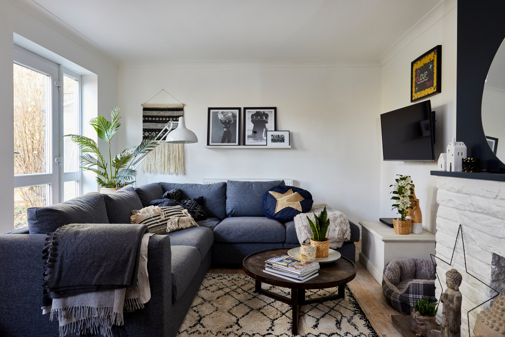 Eklektisches Wohnzimmer mit weißer Wandfarbe, braunem Holzboden, Kamin, Kaminumrandung aus Backstein, TV-Wand und braunem Boden in London