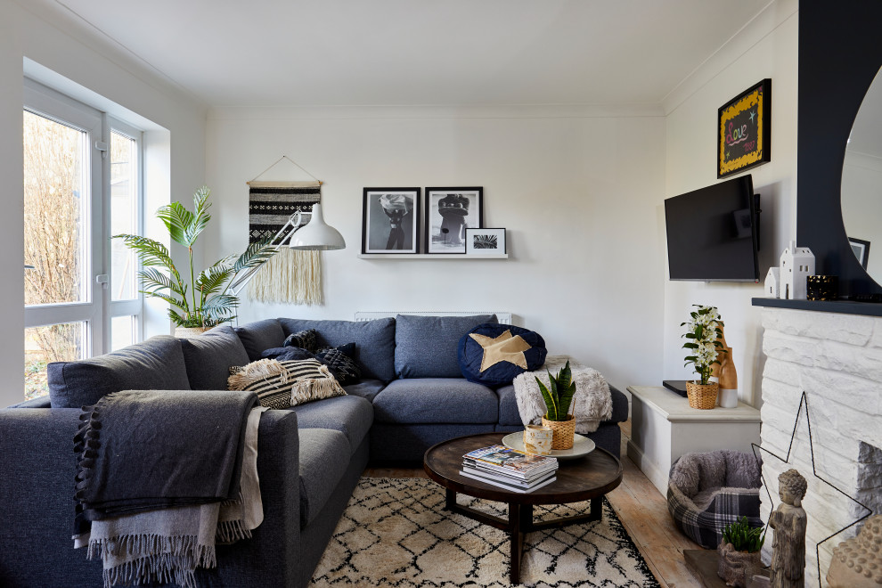 Inspiration for an eclectic medium tone wood floor and brown floor living room remodel in London with white walls, a standard fireplace, a brick fireplace and a wall-mounted tv