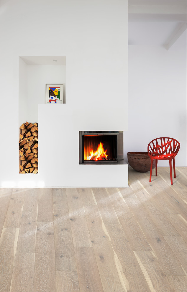 Diseño de salón abierto nórdico de tamaño medio con paredes blancas, suelo de madera clara, estufa de leña, marco de chimenea de metal y suelo blanco