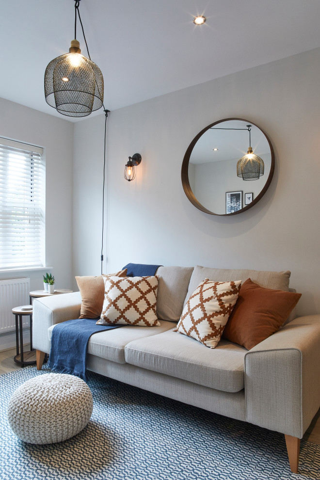 Источник вдохновения для домашнего уюта: маленькая открытая гостиная комната в скандинавском стиле с серыми стенами, полом из ламината, отдельно стоящим телевизором и серым полом для на участке и в саду