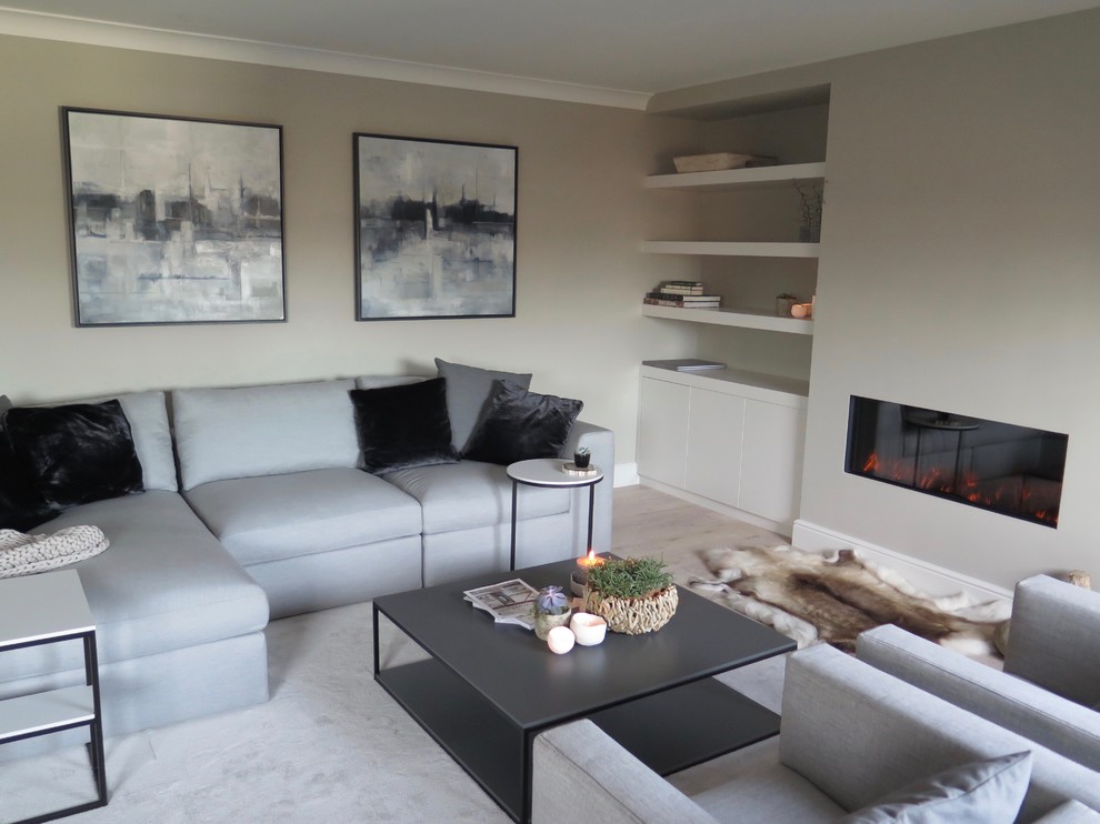This is an example of a medium sized scandi open plan living room in Cheshire with a reading nook, grey walls, light hardwood flooring, a wood burning stove, a plastered fireplace surround and a wall mounted tv.