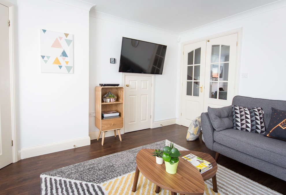 Mittelgroßes, Abgetrenntes Nordisches Wohnzimmer mit weißer Wandfarbe, Laminat, TV-Wand und braunem Boden in Berkshire