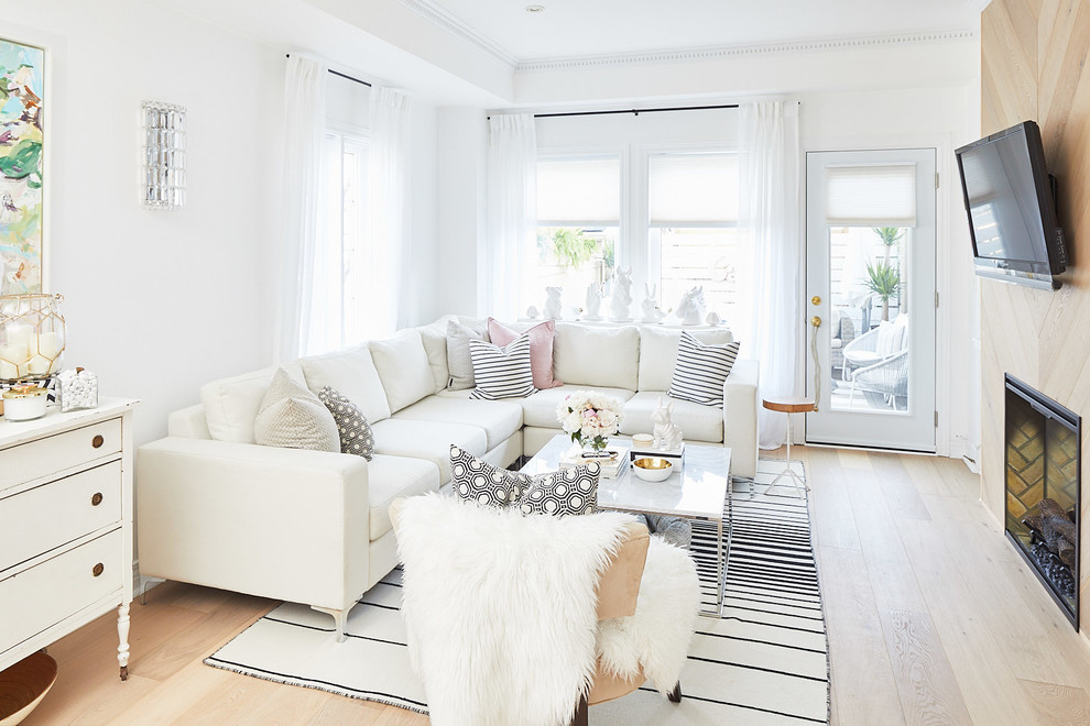 This is an example of a small scandinavian open plan living room in Toronto with white walls, limestone flooring, a standard fireplace, a wooden fireplace surround and a built-in media unit.