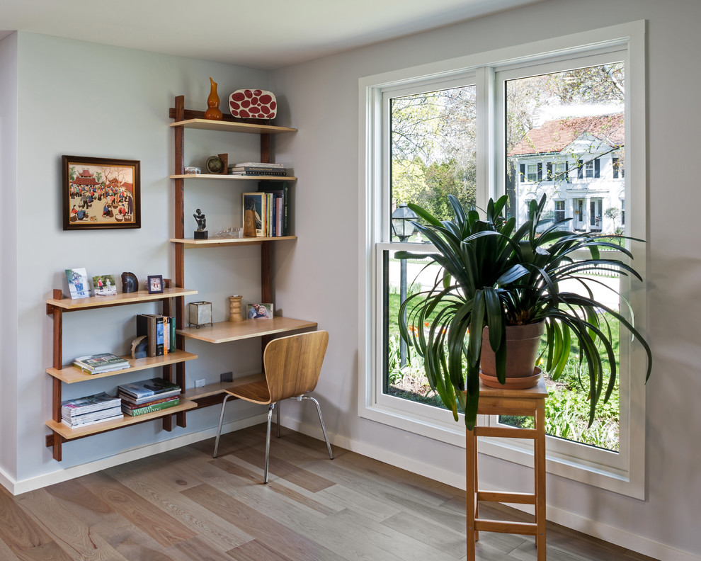 Example of a mid-sized danish open concept light wood floor living room library design in Milwaukee with white walls