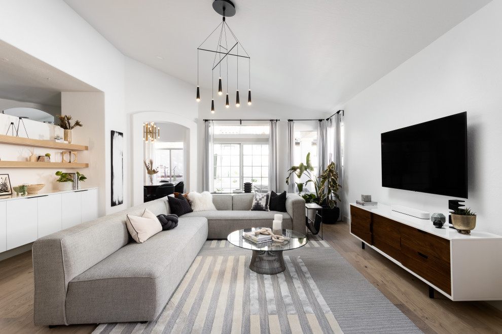 Стильный дизайн: гостиная комната в скандинавском стиле с белыми стенами, светлым паркетным полом, телевизором на стене и бежевым полом - последний тренд