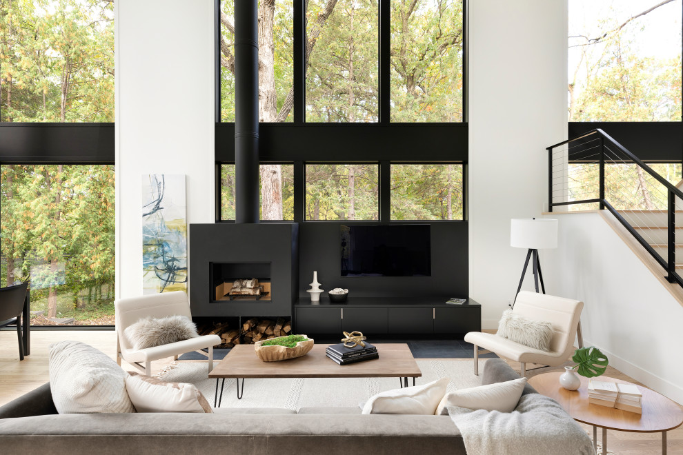 This is an example of a medium sized scandinavian open plan living room in Minneapolis with beige walls, light hardwood flooring, a wood burning stove, a metal fireplace surround, a built-in media unit and beige floors.