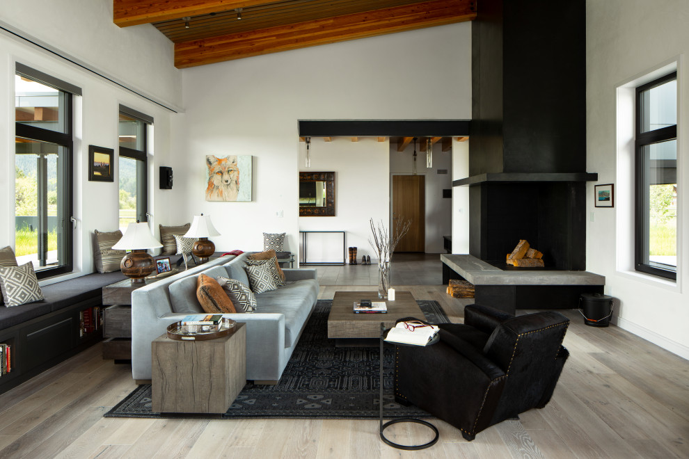 Esempio di un soggiorno design aperto con pareti bianche, parquet chiaro, camino ad angolo e pavimento grigio