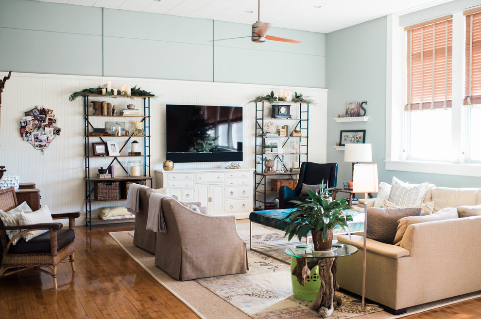 Esempio di un ampio soggiorno country aperto con pareti blu, pavimento in legno massello medio, TV a parete e pavimento marrone
