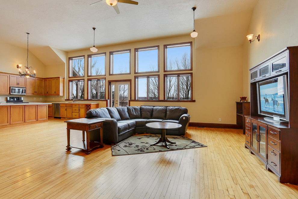 Foto de salón para visitas abierto actual grande con paredes beige, suelo de madera clara, estufa de leña, marco de chimenea de metal y televisor independiente