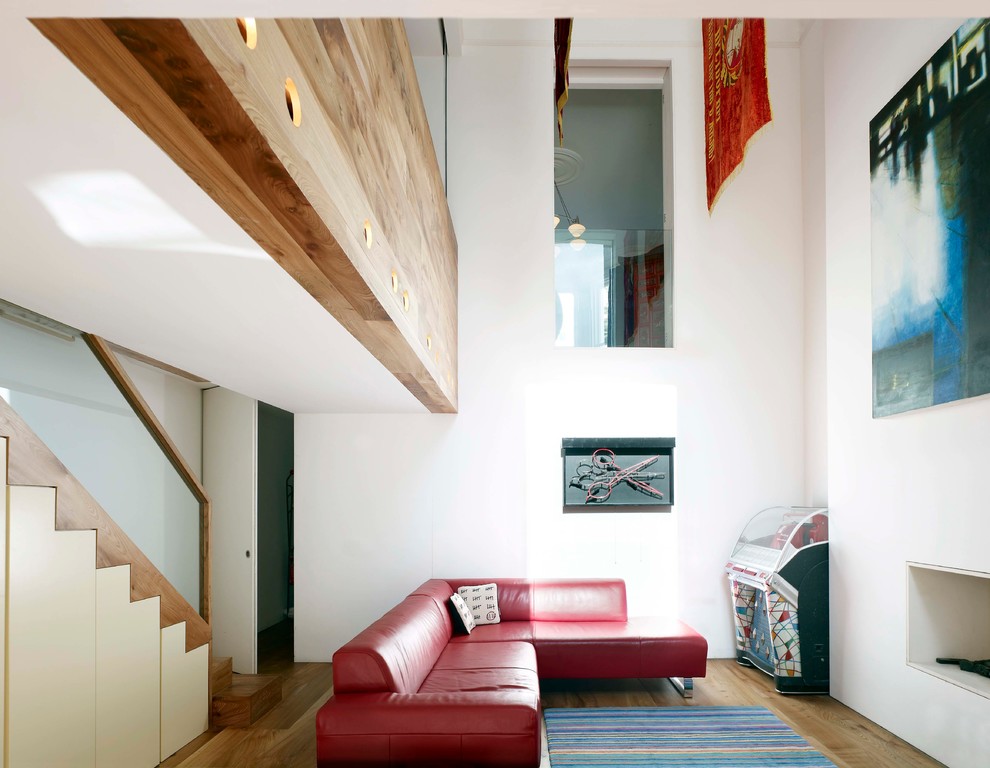 Ejemplo de salón para visitas bohemio con suelo de madera en tonos medios, chimenea lineal, marco de chimenea de yeso y paredes blancas