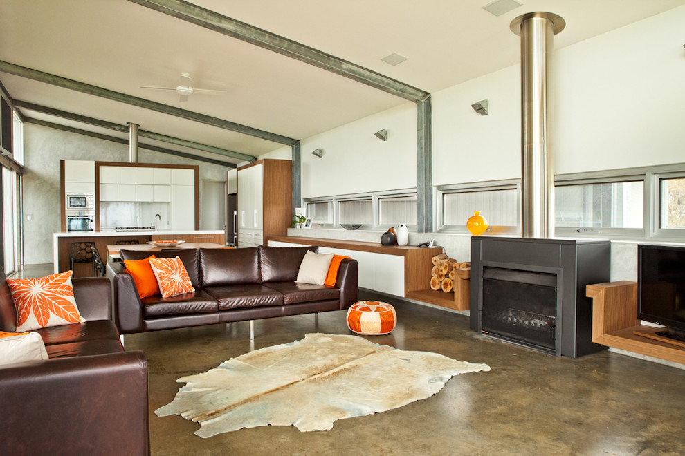 Immagine di un soggiorno minimal aperto e di medie dimensioni con pavimento in cemento, camino classico e pareti bianche