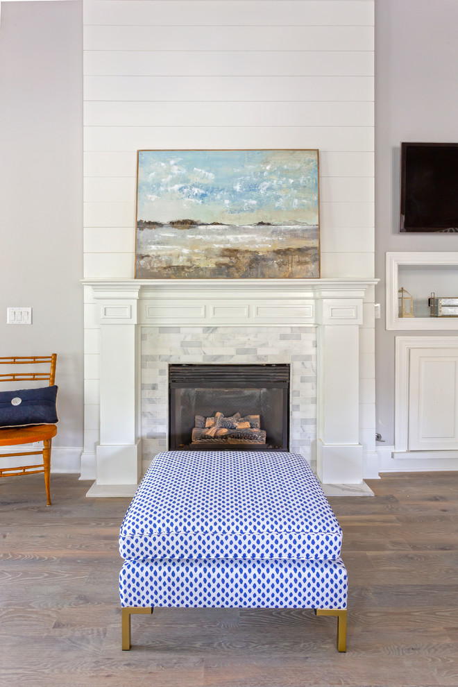 На фото: открытая гостиная комната среднего размера в морском стиле с серыми стенами, светлым паркетным полом, стандартным камином, фасадом камина из камня, телевизором на стене и серым полом