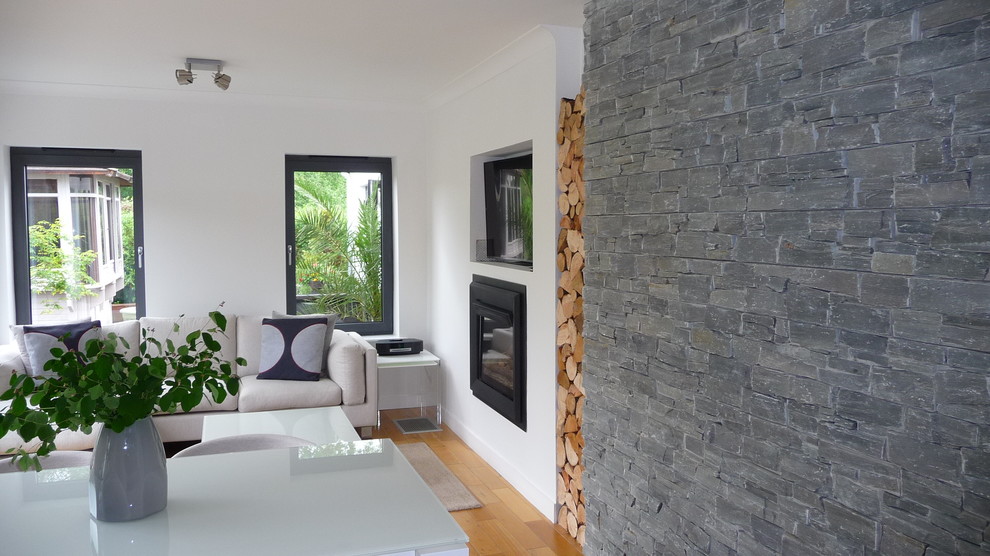 Пример оригинального дизайна: открытая гостиная комната среднего размера в скандинавском стиле с серыми стенами, темным паркетным полом, печью-буржуйкой, фасадом камина из штукатурки и скрытым телевизором