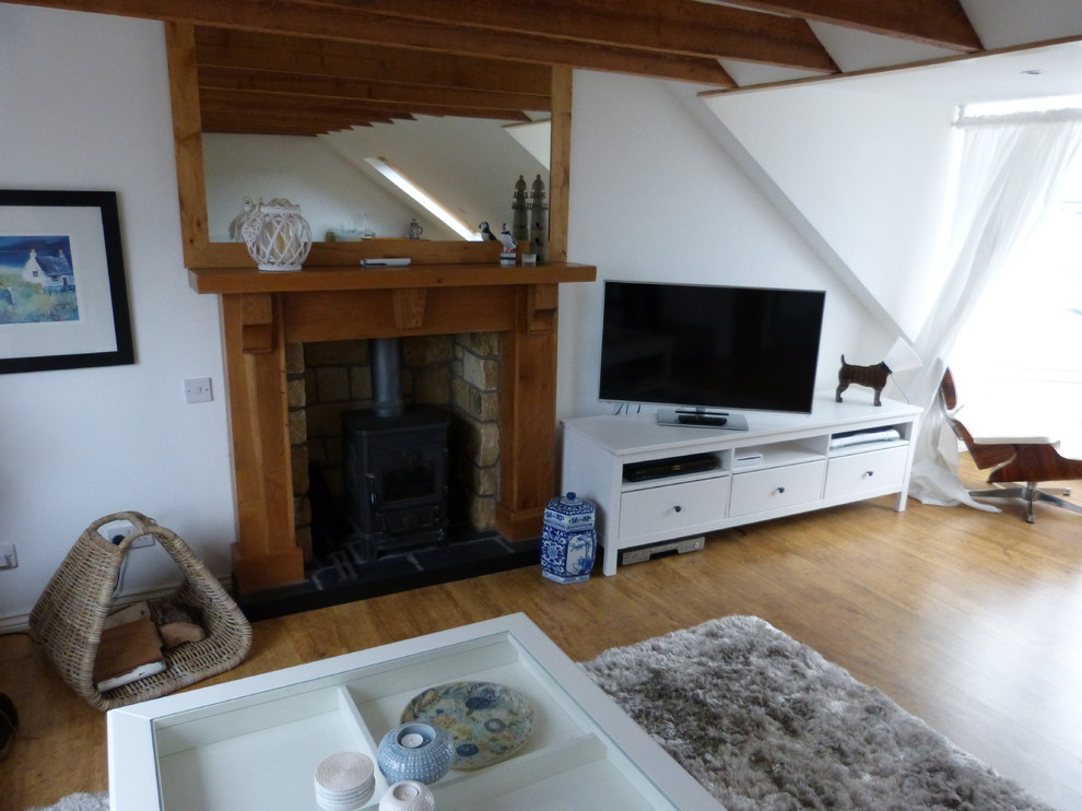 Foto på ett mellanstort eklektiskt separat vardagsrum, med vita väggar, ljust trägolv, en öppen vedspis, en spiselkrans i trä och en fristående TV
