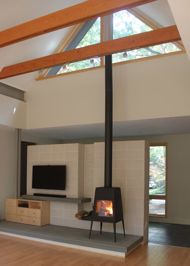 Foto di un soggiorno minimalista di medie dimensioni e aperto con pareti grigie, parquet chiaro e stufa a legna