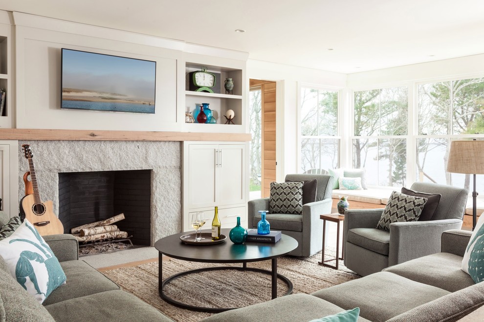 Maritimes Wohnzimmer mit weißer Wandfarbe, braunem Holzboden, Kamin, Kaminumrandung aus Stein, TV-Wand und braunem Boden in Boston