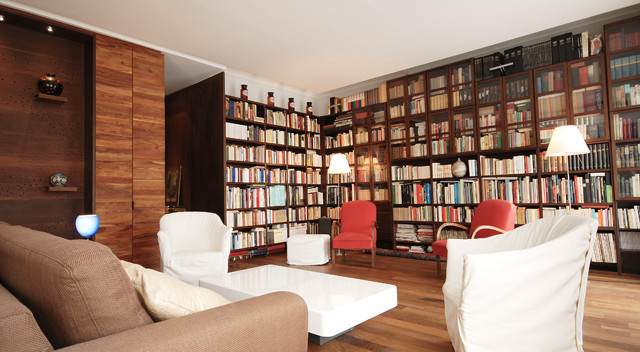 Modelo de biblioteca en casa abierta tradicional sin chimenea con paredes marrones, suelo de madera en tonos medios y pared multimedia