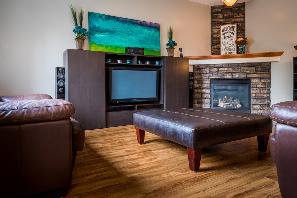 Mittelgroßes, Abgetrenntes Klassisches Wohnzimmer mit Eckkamin, Kaminumrandung aus Stein, braunem Boden, beiger Wandfarbe, dunklem Holzboden und verstecktem TV in Calgary
