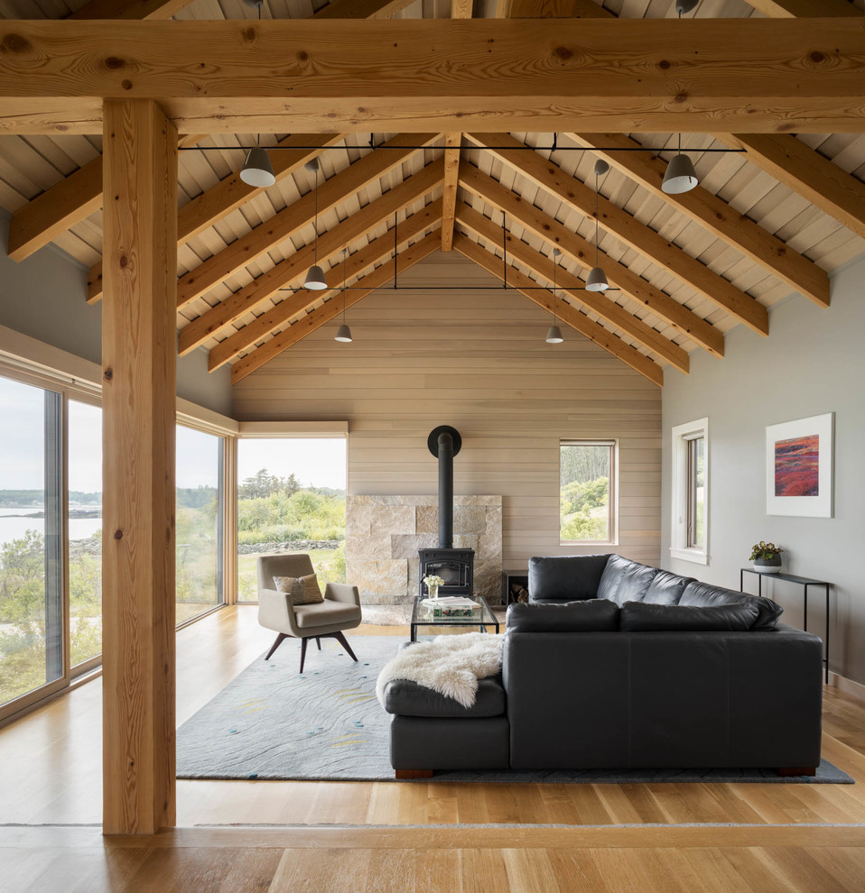 Immagine di un soggiorno stile marinaro con pareti grigie, pavimento in legno massello medio, stufa a legna e pavimento marrone