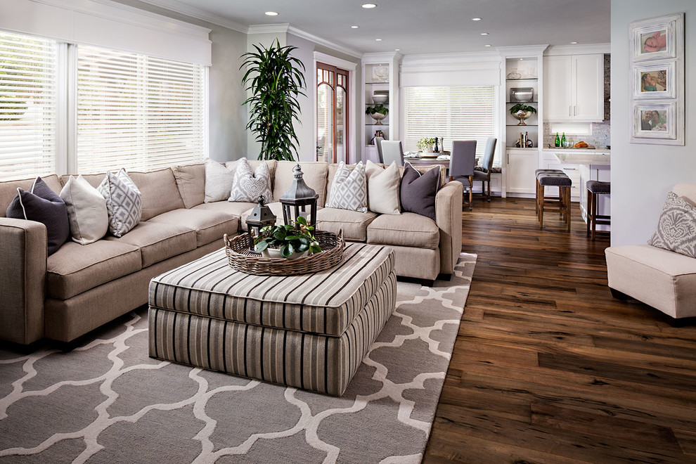Imagen de salón abierto costero con suelo de madera en tonos medios y paredes grises
