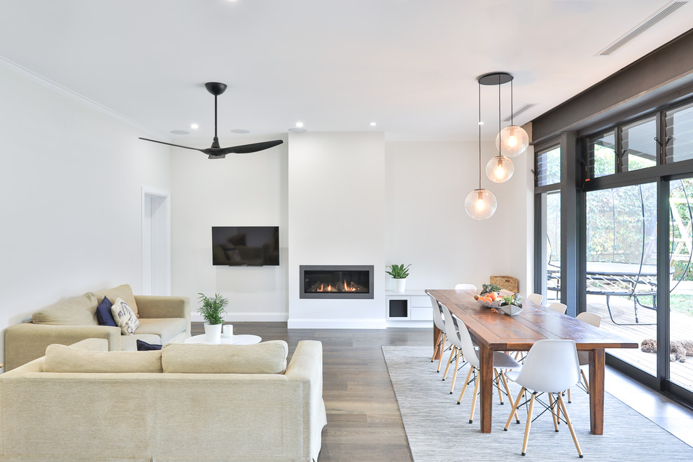 Idée de décoration pour un grand salon design ouvert avec un mur blanc, un sol en bois brun, un manteau de cheminée en métal, un téléviseur fixé au mur, un sol marron et une cheminée ribbon.
