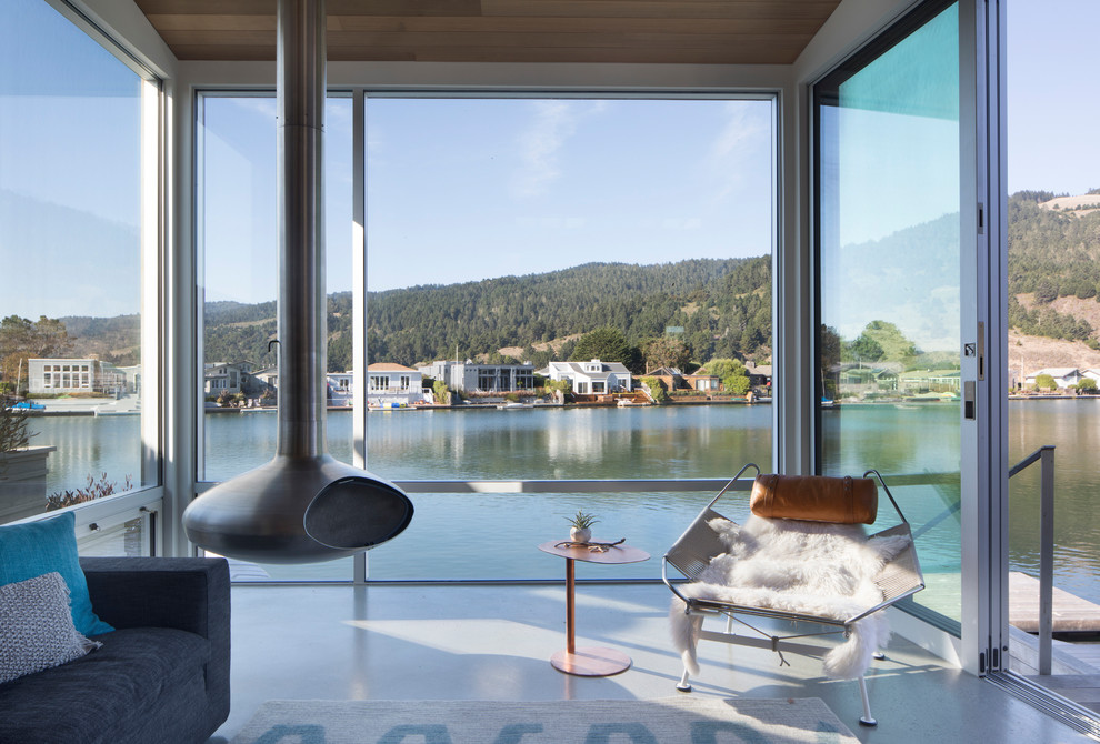 Идея дизайна: открытая гостиная комната в современном стиле с подвесным камином и серым полом