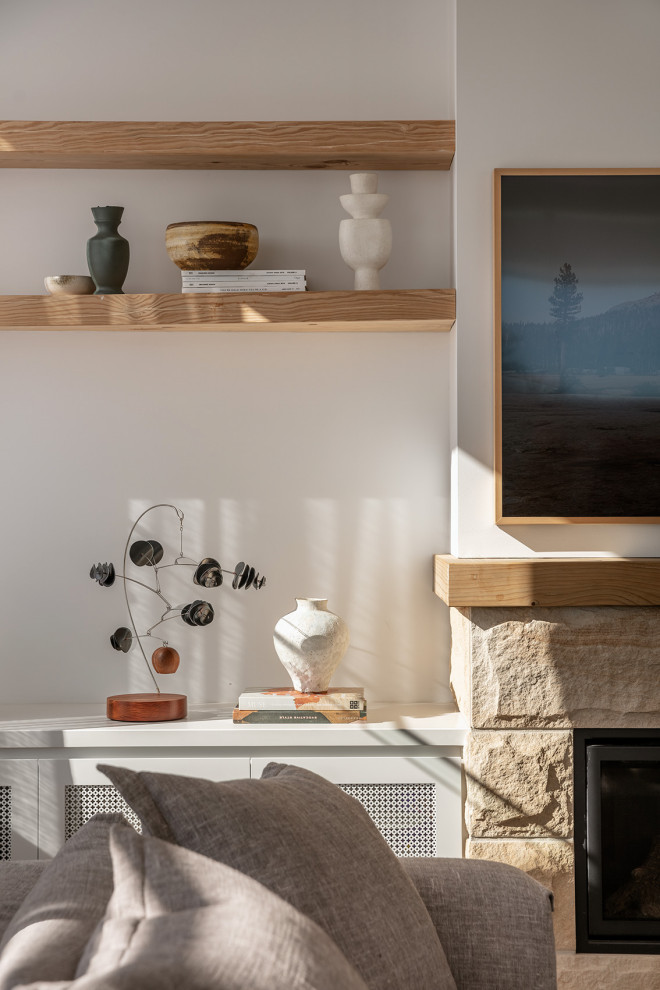 Modern inredning av ett vardagsrum, med vita väggar, ljust trägolv, en standard öppen spis och en spiselkrans i sten