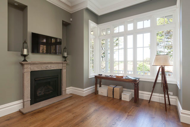 Cette photo montre un salon tendance fermé avec une salle de réception, un mur vert, un sol en bois brun, une cheminée standard, un manteau de cheminée en pierre et un téléviseur fixé au mur.
