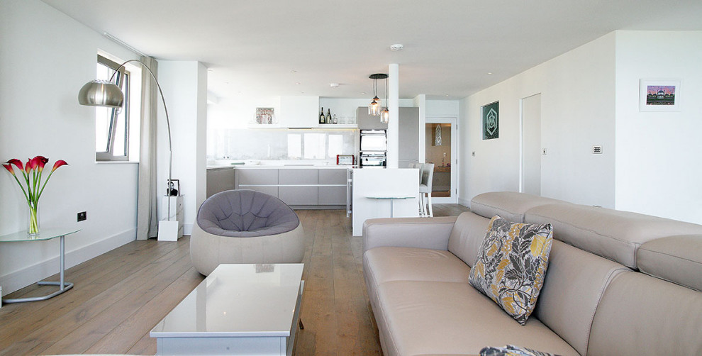 На фото: большая открытая гостиная комната в современном стиле с белыми стенами, паркетным полом среднего тона, телевизором на стене, коричневым полом и многоуровневым потолком