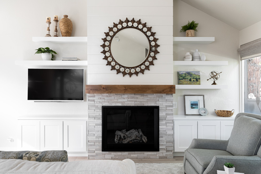 他の地域にある高級な小さなトランジショナルスタイルのおしゃれなLDK (白い壁、クッションフロア、標準型暖炉、石材の暖炉まわり、壁掛け型テレビ) の写真