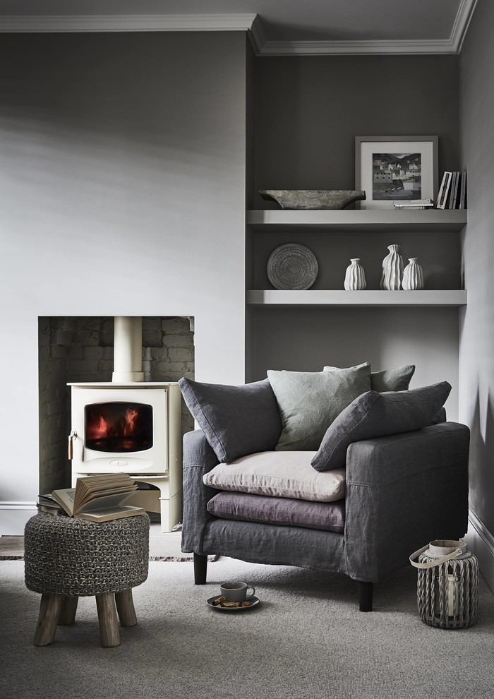 Inspiration for a small beach style enclosed living room in Other with grey walls, carpet, a wood burning stove, a brick fireplace surround and grey floors.