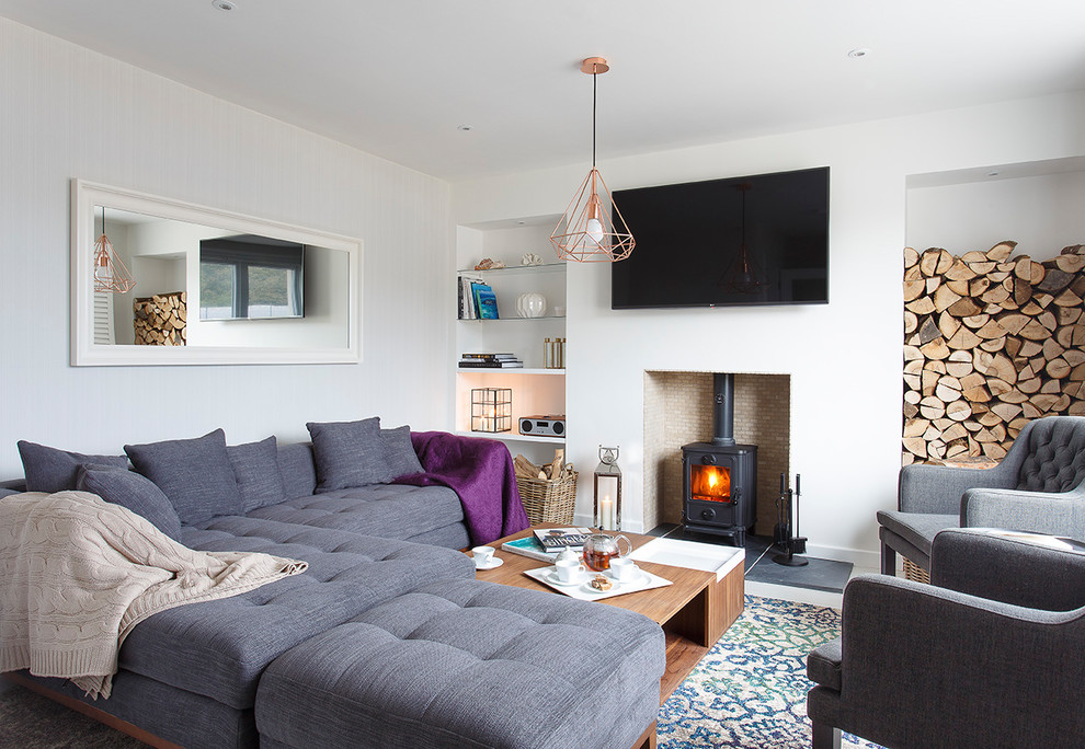 Foto di un soggiorno design con pareti bianche, moquette, stufa a legna, cornice del camino in metallo e TV a parete