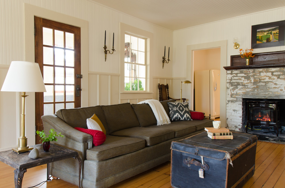 Maritimes Wohnzimmer mit Kaminumrandung aus Backstein, weißer Wandfarbe und braunem Holzboden in Portland