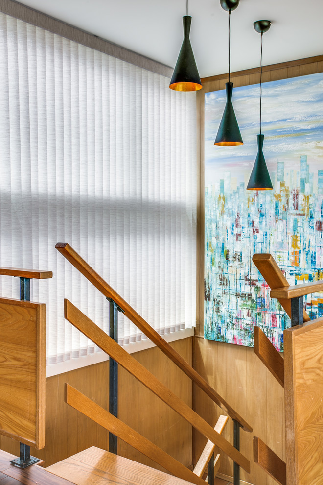 Immagine di un grande soggiorno minimalista aperto con libreria, pareti blu, pavimento in legno massello medio, TV a parete e pavimento marrone