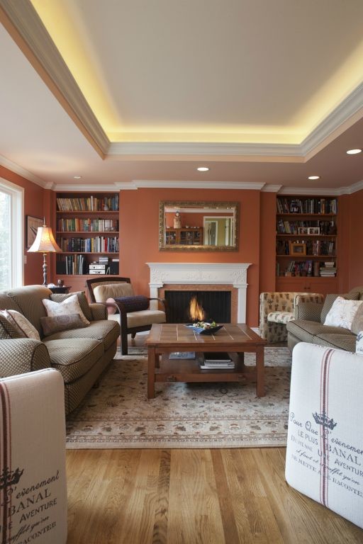 Foto di un grande soggiorno chic aperto con libreria, pareti arancioni, parquet chiaro e camino classico