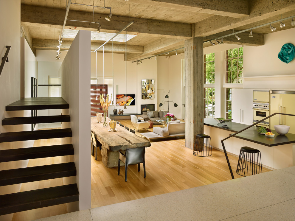 Geräumiges, Repräsentatives, Offenes Industrial Wohnzimmer mit weißer Wandfarbe, hellem Holzboden, Kamin und beigem Boden in Austin