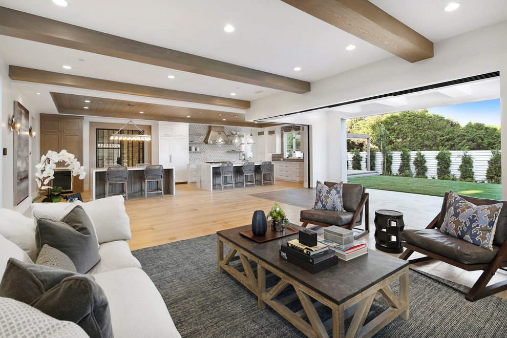 Inspiration for a large modern open concept light wood floor living room remodel in Orange County with white walls, a wall-mounted tv and a standard fireplace