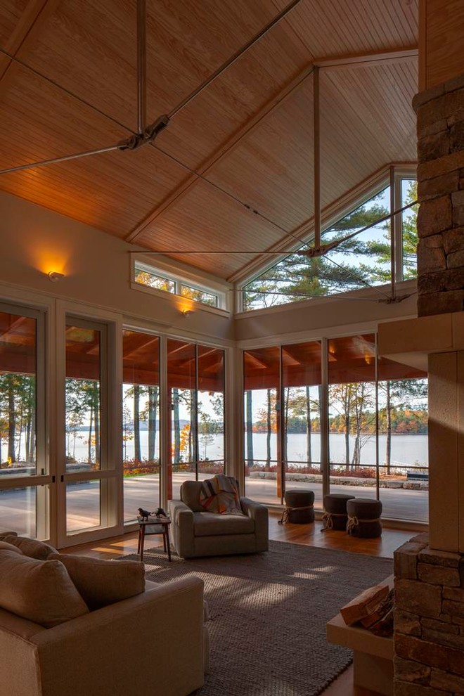 Großes, Offenes Modernes Wohnzimmer mit beiger Wandfarbe, hellem Holzboden, Kamin und Kaminumrandung aus Stein in Portland Maine