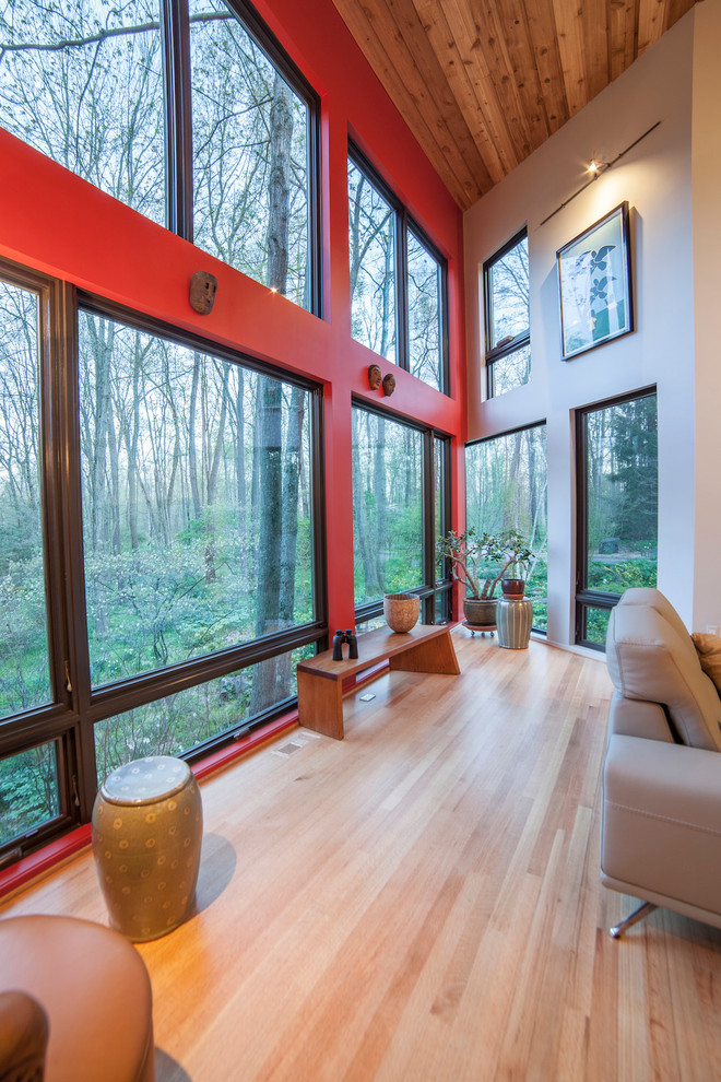 Modelo de salón para visitas abierto contemporáneo de tamaño medio sin televisor con suelo de madera clara, chimenea lineal, marco de chimenea de hormigón y paredes rojas