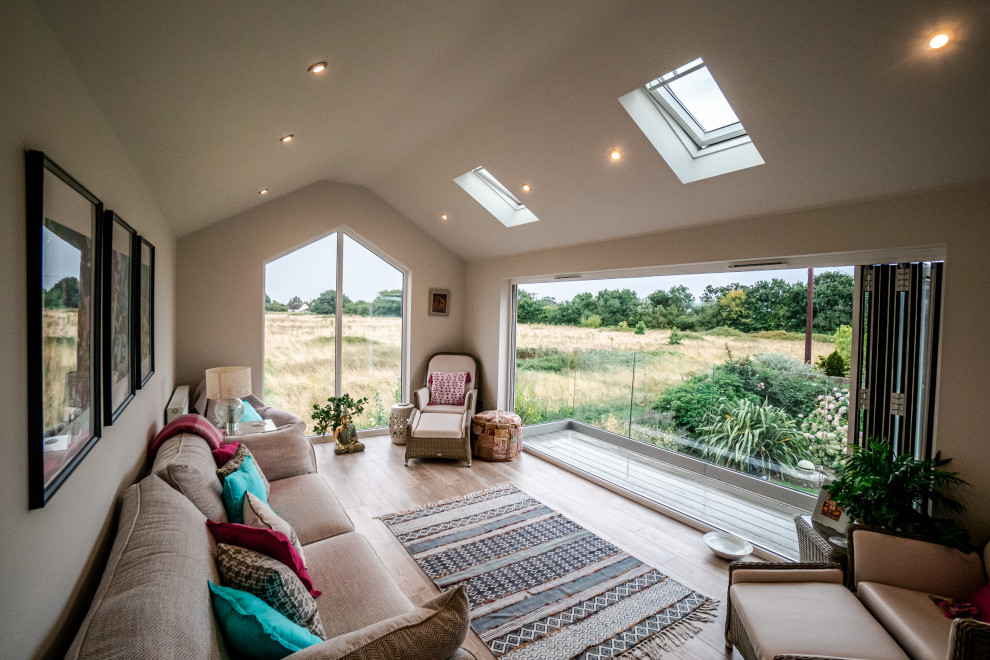 Mittelgroßes Stilmix Wohnzimmer ohne Kamin mit weißer Wandfarbe und braunem Boden in Essex