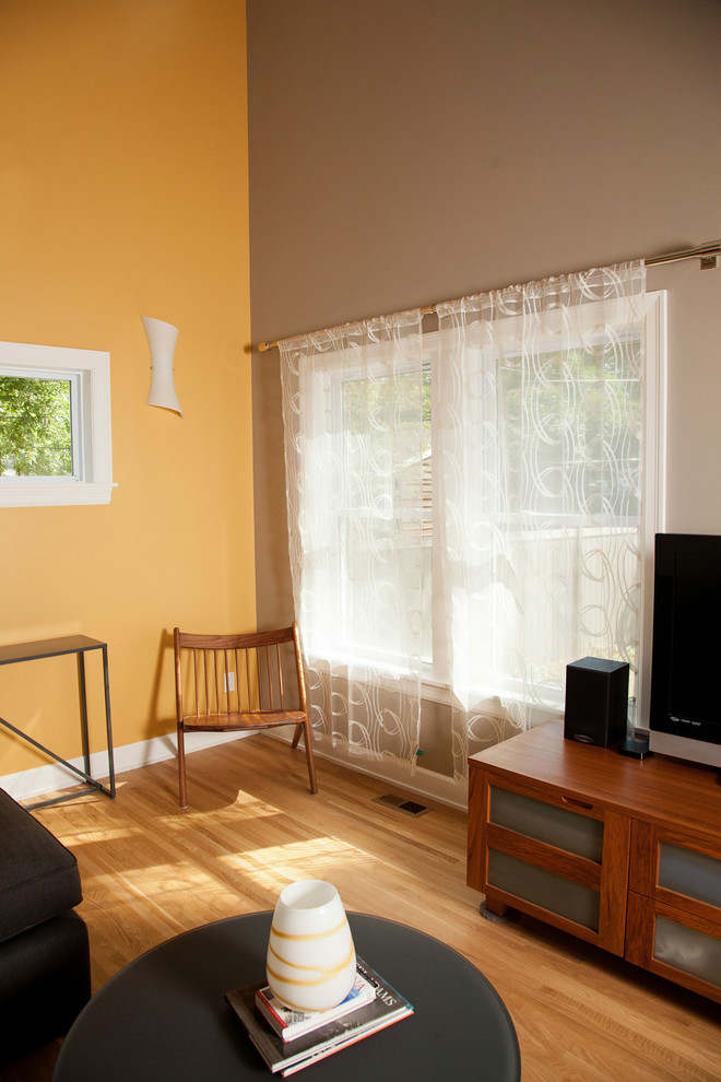 Идея дизайна: открытая гостиная комната среднего размера в современном стиле с желтыми стенами, светлым паркетным полом и отдельно стоящим телевизором без камина