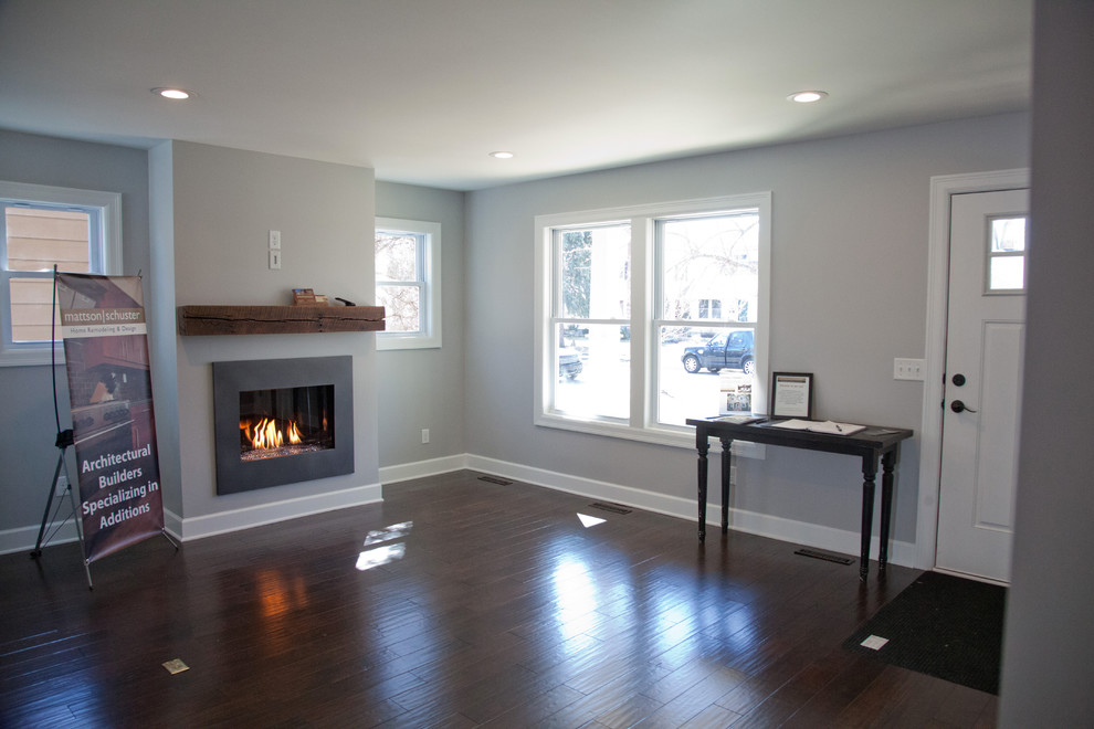 This is an example of a large classic enclosed living room in Minneapolis with grey walls, dark hardwood flooring, a standard fireplace, a metal fireplace surround and a wall mounted tv.